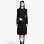 Woman wearing a black dress with a black and white handbag on a white background